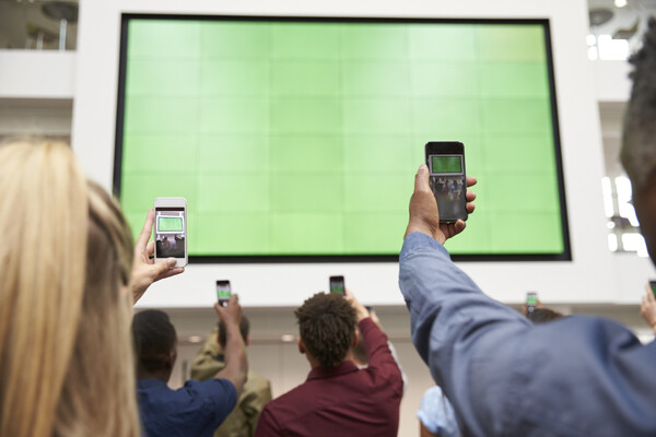 mutliple men holding phone to screen